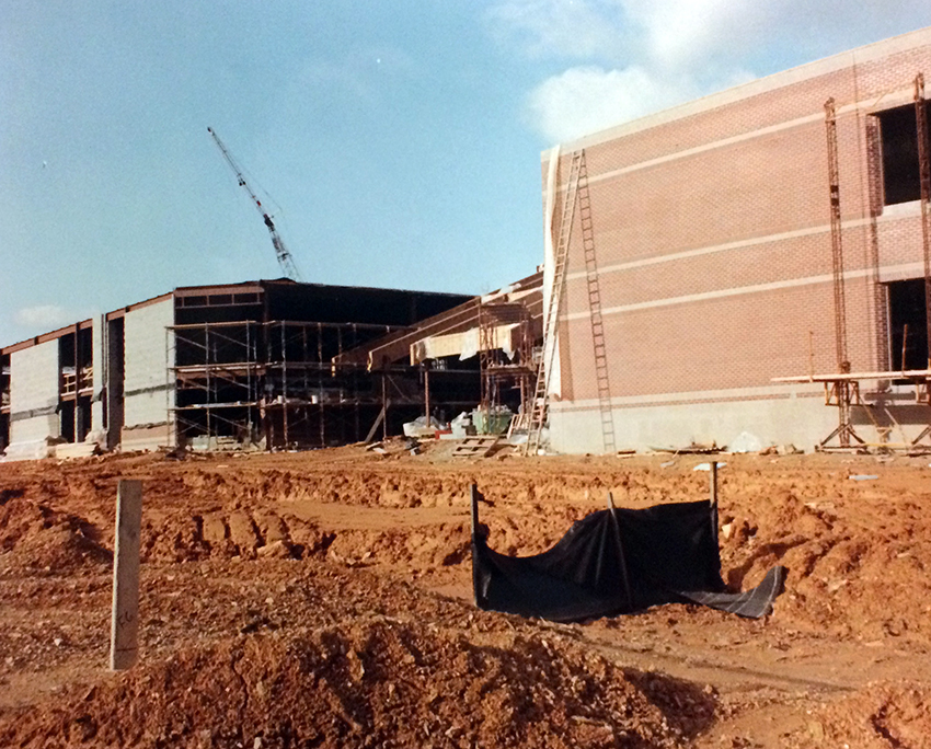 Photograph of Aldrin Elementary School during construction. The rear of the building is shown. The cinderblock walls and portions of the roof are complete. A portion of the building closest to the camera has a brick veneer in place. The roof over the main lobby is incomplete. Scaffolding can be seen in the distance against the far wing of the building.