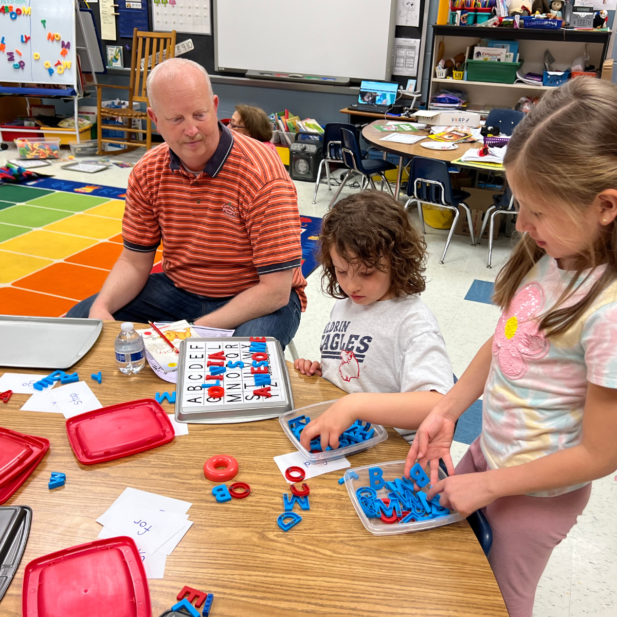 A family working on phonics skills using magnetic letters.