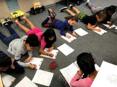 image of students writing in their flexible seating on the floor