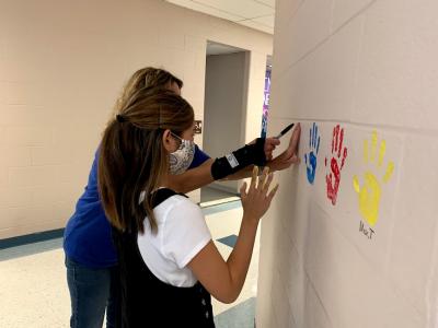 6th grade hand prints students getting hands painted from them to put their handprint on the hall wall